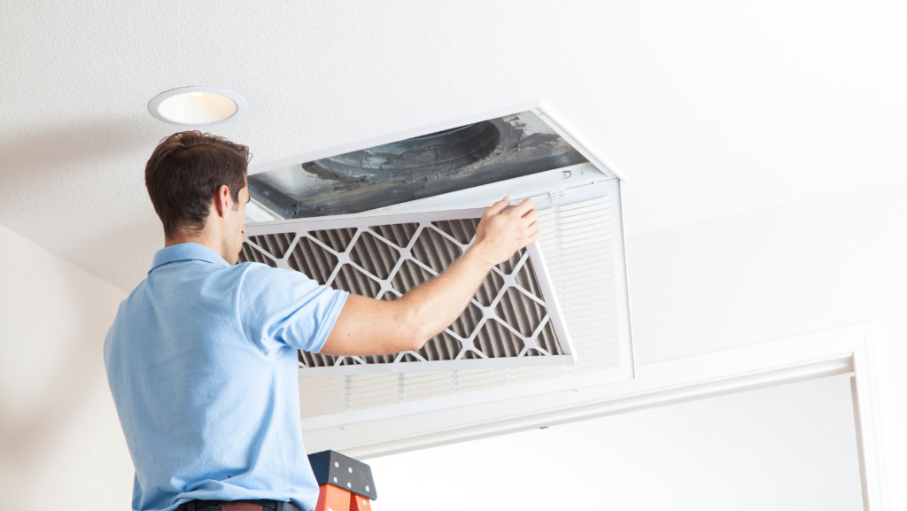 A man on a ladder replacing an air filter