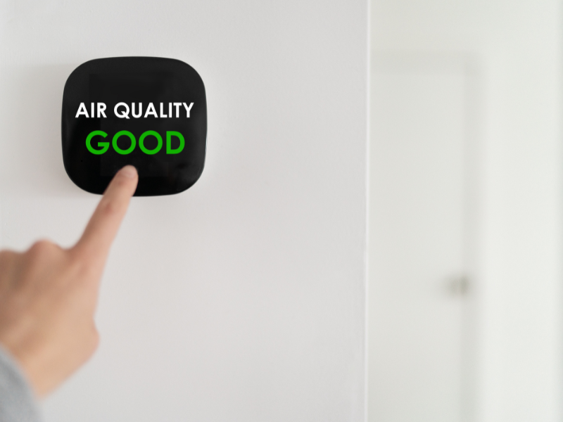 Person pressing a button that says indoor air quality good