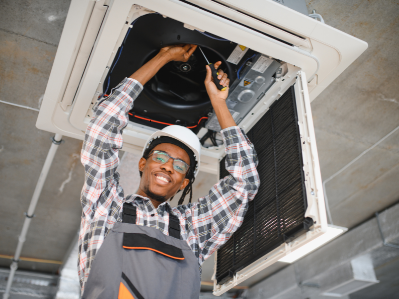 An HVAC tech looking down from a vent smiling